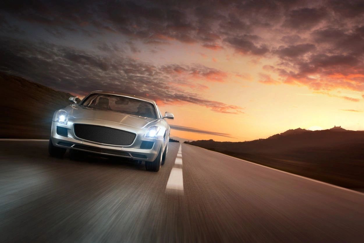 Luxury silver car on highway at sunset